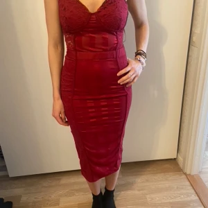 Vinröd spetsklänning PrettyLittleThing - Säljer en vinröd långklänning från PrettyLittleThing i storlek 38. Klänningen har spetsdetaljer upptill, figurnära passform och v-ringad urringning. Materialet är polyester och klänningen har dragkedja i sidan. Perfekt för dig som vill ha en snygg och trendig look.