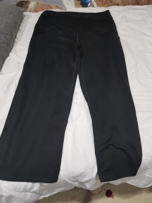 Svarta mjukisbyxor med snörning - Svarta mjukisbyxor med bred midja och snörning framtill. Byxorna har en loose passform och är tillverkade i mjukt material som passar perfekt för chill eller träning. Stilrena och enkla att matcha med en hoodie eller t-shirt. De är för barnmorska.