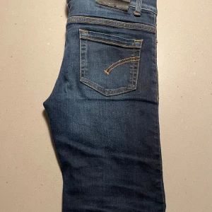 Dondup George skinny jeans blå - Snygga mörkblå jeans från Dondup, modell George Skinny Fit. Klassisk femficksdesign med kontrastsömmar och smal passform. Tillverkade i slitstark denim med en cool tvättad look. Perfekta för dig som gillar en modern och tajt stil.