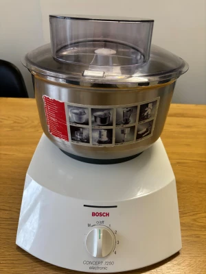 Bosch Concept 7200 Electronic - Bosch Concept 7200 Electronic köksmaskin med stor rostfri skål och genomskinligt lock. Flera hastighetslägen och robust konstruktion. Skålen har instruktioner och tillbehörsbilder. Maskinen ser välvårdad ut med mindre yttre slitage. Perfekt för bakning och matlagning.