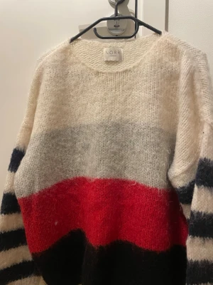 Randig stickad tröja från NORR - Fluffig tröja från NORR. Fint skick förutom en liten sminkfläck vid kragen . 