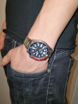 Seiko dyckarklocka - Bilderna visar ingen väst, utan en Seiko automatisk dykarklocka med blå och röd vridring samt silvrigt armband. Nypris 4000kr så jävligt bra deal lite slitage på vridningen annars mycket bra skick. Även tillköpt band klockarmband.