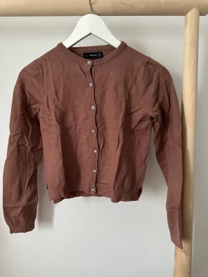 Kofta med glittriga knappar från Zara - Supersöt kofta från Zara i stickad material, med långa ärmar och glittriga pärlknappar framtill. Rund halsringning och ribbade muddar.