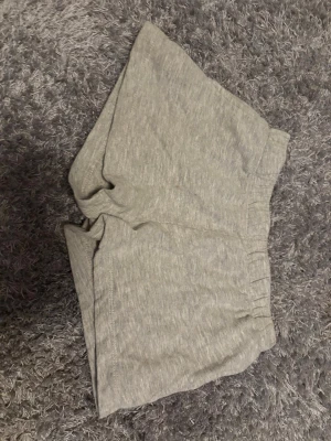 Grå mjuka shorts från lager 157! - Säljer ett par gråa shorts från lager 157 i storlek 140. De har en elastisk midja och är gjorda i mjukt bomullsmaterial, perfekta för chill dagar. Passformen är normal och färgen är ljusgrå. Enkla och sköna att ha på sig.