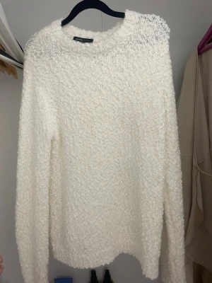Vit fluffig stickad tröja Mywear - Mysig vit stickad tröja från Mywear med fluffig och bubblig struktur. Tröjan har rund hals och långa ärmar, perfekt för att hålla sig varm under kyliga dagar. Passar dig som gillar en enkel men ändå unik look.
