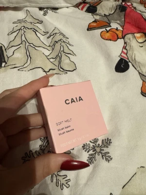 CAIA Soft Melt Blush Balm Butter Toast - Säljer en CAIA Soft Melt blush balm i färgen Butter Toast. Kommer i en söt ljusrosa fyrkantig förpackning med silvertext. Innehåller 3,9 g krämrouge som ger en naturlig och fräsch look till kinderna. Perfekt för dig som gillar smink med mjuk finish.