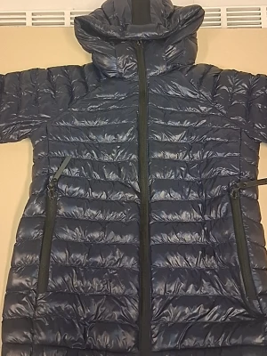 Mörkblå dunjacka Peak Performance - Snygg mörkblå dunjacka från Peak Performance med huva och två stora dragkedjeförsedda fickor. Jackan har quiltad design och ribbade muddar vid ärmslut. Perfekt för kalla dagar och har en stilren look som funkar till många outfits.Används några gånger,priset är inte hugget i ett sten