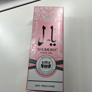 Shumukh Keratin Hair Oil 180ml - Shumukh Keratin Hair Oil med naturlig essens och elegant doft. Kommer i en rosa och silverfärgad förpackning med blommönster. Innehåller keratin och vitaminer som ger näring, glans och skydd mot friss. Flaskan rymmer 180 ml och har en lyxig design med guldfärgat lock.