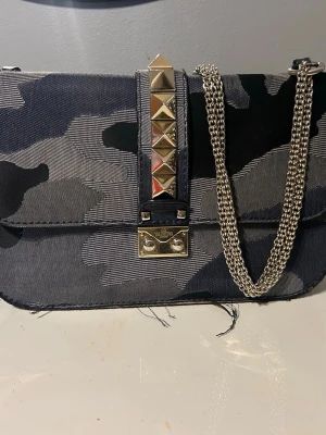 Valentino väska  - Så cool och unik garavani glamlock väska, Såkllart äkta! Dustbag medkommer, det finns slitningar på väskan men den är i bra skick. Kan gå ner i pris vid snabb affär! 