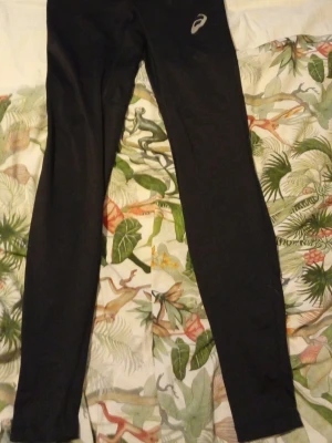 Träningsleggings från Asics - Svarta leggings från Asics i storlek S, perfekta för träning. De har en slim och tight passform med elastiskt material som ger bra rörelsefrihet. Diskret Asics-logga på höften. Snygga och funktionella för gymmet eller löprundan.