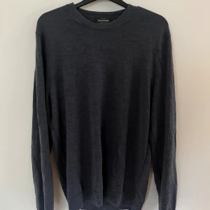 Mörkgrå/blå merinoullströja Dressmann L - Snygg mörkgrå/blå tröja från Dressmann i 100% merinoull. Klassisk rund hals och långärmad modell som är perfekt för kyliga dagar. Materialet är mjukt och skönt mot huden och ger en stilren look. Passar dig som gillar enkel och tidlös stil.