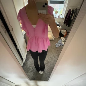 Rosa blus från Lindex  - helt oanvänd rosa blus från Lindex i storlek S. Den har fyra knappar där fram och volanger runt hela!