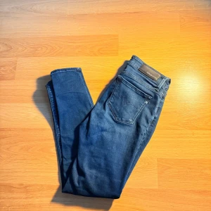 Replay blå jeans - Snygga blå jeans från Replay med klassisk femficksdesign och tydliga sömmar. Jeansen har en mörk tvätt och smal passform som sitter tajt längs benen. Materialet är stretchigt jeans och midjan är normal. Perfekt för dig som gillar stilrena och moderna jeans. 