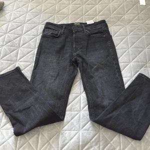 Svarta tapered jeans från Jack & Jones - Snygga svarta jeans från Jack & Jones, modell Tapered/Mike. Jeansen har klassisk femficksdesign, normal passform och avsmalnande ben. Materialet är mjukt och slitstarkt denim med en mörk tvätt. Perfekt för dig som gillar stilrena och bekväma jeans.