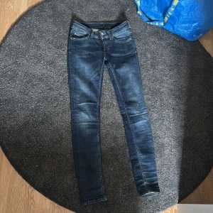 Mörkblå jeans från Tiger of Sweden - Snygga mörkblå jeans från Tiger of Sweden med klassisk femficksdesign och diskreta slitningar. Jeansen har låg midja och smal passform hela vägen ner. Materialet är stretchigt jeans för extra komfort. Säljer dem för att de var för små på mig