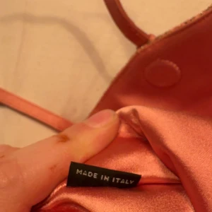 Rosa axelväska från Miu Miu i brokad - Unik rosa axelväska från Miu Miu, tillverkad i Italien. Väskan har ett broderat tyg med guldiga detaljer och flera dekorativa remmar i rosa skinn. Justerbar axelrem och snygg metallogo framtill. Perfekt för dig som vill sticka ut med en lyxig accessoar.