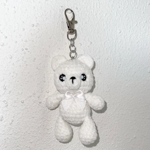 En virkad nallebjörn nyckelring! - Virkad nallebjörn nyckelring, den är mjuk och gullig. Nallebjörnen har även en liten rosett av tyg! Jag har virkat den själv, och den har Säkerhetsögon och är stoppad med fyllnadsvadd.