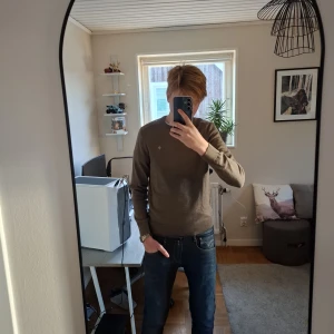 Beige Merino ull stickad tröja från Morris - Nypris 1700 kr.  Säljer en stilren beige stickad tröja av kvalitet Merino ull från Morris . Tröjan har ribbade muddar och är perfekt för lager-på-lager under hösten och vintern. Passar dig som gillar klassisk och clean stil.