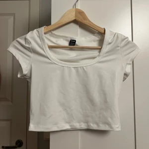 Vit croppad topp från SHEIN - Säljer en vit croppad topp från SHEIN i storlek XS. Toppen har korta ärmar och en rund, djup urringning. Enkel och stilren design som passar perfekt till jeans eller kjol. Materialet är mjukt och stretchigt för en bekväm passform.