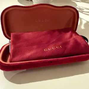 Gucci solglasögon brun fyrkantig - Snygga solglasögon från Gucci med fyrkantig form och brun transparent båge. Kommer med originalfodral i röd sammet och matchande röd påse med guldfärgad logga. Perfekt accessoar för att lyfta din stil.