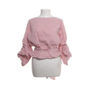 Randig omlottblus från Zara Woman - Säljer en snygg randig blus från Zara Woman i vitt och rött. Blusen har omlottmodell med knyt i midjan, voluminösa ärmar och v-ringning i ryggen. Perfekt för dig som gillar trendiga detaljer och en cool siluett.