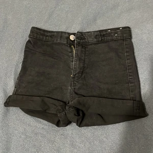 Svarta high waist denimshorts &Denim - Svarta high waist shorts från &Denim med klassisk femficksdesign, uppvikta benslut och dragkedja framtill. Snygg och enkel modell i denim som passar perfekt till sommaren. Gylf med knapp och dragkedja, bakfickor och bälteshällor.