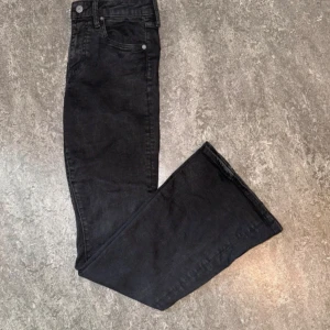 Svarta flare jeans från S. Denim - Svarta jeans från S. Denim i klassisk flare-modell med hög midja. Jeansen har fem fickor, dragkedja och knapp framtill. Materialet är denim och passformen är slim upptill med utsvängda ben. Perfekta för dig som gillar en retroinspirerad look.