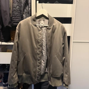 Olivgrön bomberjacka från H&M - Snygg olivgrön bomberjacka från H&M med ribbade muddar och krage. Sjukt stilren & cool! Storlek är S/M beroende på hur man vill att den ska sitta. 
