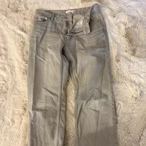 Grå jeans från Gina, storlek 36 - Snygga grå jeans från Gina. Byxorna har rak passform, dragkedja och knapp i midjan samt bälteshällor. Materialet är mjukt och slitstarkt jeans, perfekt för dig som gillar enkel och stilren look.