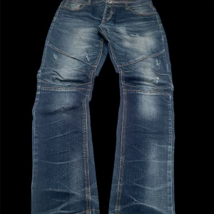 Blå wide archive 2000s vintage jeans  - NOT NUDIE! Säljer ett par blå jeans med breda ben och coola sömdetaljer över knäna. Jeansen har slitna partier och en tvättad look med kontrastsömmar. Klassisk femficksmodell och knappgylf. Perfekt för dig som gillar streetsti. Waist 47.5cm Full length 108cm