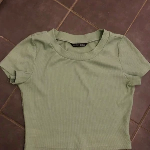 Ljusgrön ribbad croppad topp SHEIN - Säljer en ljusgrön croppad topp från SHEIN med korta ärmar och rund halsringning. Toppen är ribbad och har tight passform.