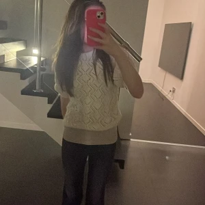 Vit stickad tröja från Zara - Supersöt vit stickad tröja från Zara med korta puffärmar och snyggt hålmönster. Tröjan har rund hals och ribbade muddar vid ärmslut och nederkant. Perfekt för dig som gillar en chill och trendig look med lite extra detaljer.