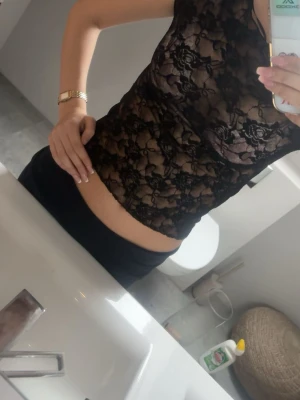 Svart långärmad spetsblus - Snygg svart långärmad blus i genombruten spets med blommigt mönster. Tight passform och rund halsringning. Perfekt att styla med ett linne under för en trendig look.