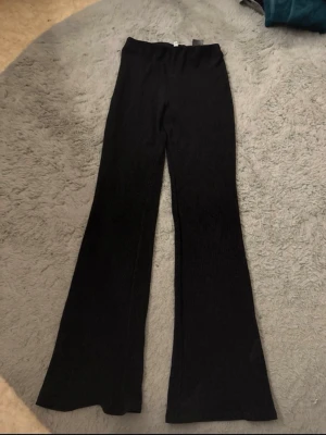 Svarta utsvängda byxor  -  De har hög midja och är tillverkade i ett mjukt, stretchigt material som sitter skönt på kroppen. Inget fel på dom