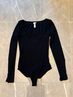 Svart långärmad body från H&M - Snygg svart långärmad body från H&M med fyrkantig ringning. Använd fåtal gånger.