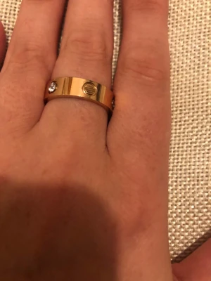 Leve ring i guldpläterad med diamant - Säljer en ikonisk Leve ring i guldpläterad med en infattad diamant och de klassiska skruvdetaljerna runt om. Ringen har en stilren och tidlös design som passar perfekt för dig som gillar lyxiga accessoarer. 