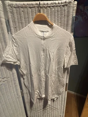 Vit kortärmad topp från Zara använt 2-3 gånger  - Säljer en vit kortärmad topp från Zara med hög krage och half zip-dragkedja framtill. Toppen har en clean look och är tillverkad i mjukt material som känns skönt mot huden. Perfekt till jeans eller kjol för en enkel men snygg outfit.