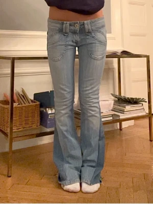 Ljusblå bootcut jeans med låg midja - Säljer ett par ljusblå bootcut jeans med låg midja och snygga detaljer. Midjemått-39cm. Innebenslängd 81cm. Byxorna va utsprungligen bootcut men omsydda till ännumer!⭐️⭐️🩷 