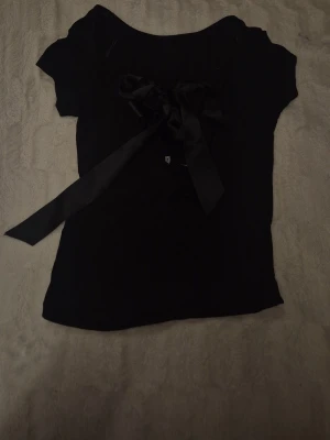 Topp med gullig rosett  - Säljer en fin tröja med öppen rygg och rosett då den ej kommer till använd längre💕