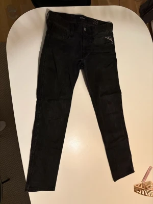 Svarta Replay jeans slimfit - Säljer ett par svarta jeans från Replay i rak modell. Klassisk femficksdesign med knappgylf och Replay-logga. Jeansen har en stilren look och passar perfekt till en avslappnad streetstyle. Materialet är slitstarkt jeans i bomull.