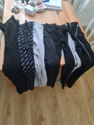 Flera leggings i svart och grått - Säljer ett gäng leggings i olika stilar och färger, mestadels svarta och gråa. Några har mönster som ränder och text, vissa är enfärgade. Perfekt för dig som vill ha flera alternativ till hösten och vintern!