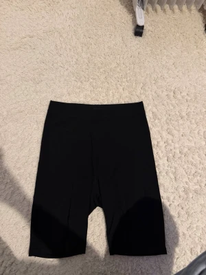Svarta cykelshorts från Even&Odd - Säljer ett par svarta cykelshorts från Even&Odd. De har en enkel och clean design med midjehög passform och stretchigt material som sitter skönt på kroppen. Perfekta till sommaren eller när du vill ha en sportig look. Storlek M ordpris: minns inte men säljer för 50kr plus frakt