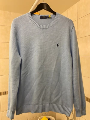 Polo Ralph Lauren Sweater - Ljusblå stickad tröja från Polo Ralph Lauren med rund halsringning och klassisk broderad logga på bröstet. Tröjan är lite smutsig vid ärmensslut, men det går att ta bort den och kan tas bort för seriösa köpare. Först till kvarn den är i princip helt ny.
