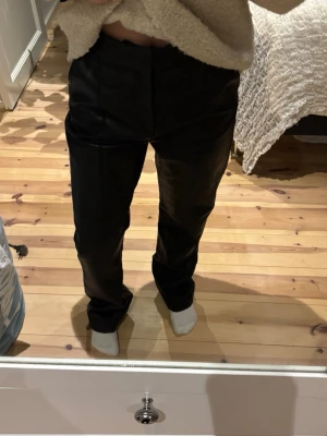 Svarta fuskskinnbyxor Gina Tricot - Snygga svarta byxor i fuskskinn från Gina Tricot. Modellen har raka ben, normal passform och högre midja. Stängs med dragkedja och knapp framtill. Pris kan diskuteras :)