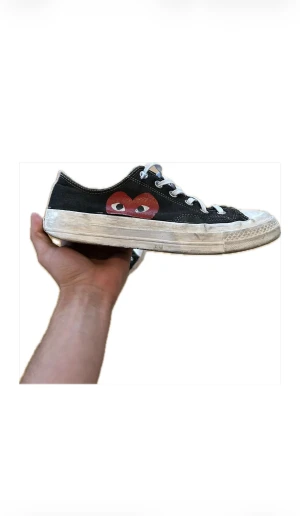 Converse Play Comme des Garçons sneakers - Svarta Converse Play Comme des Garçons sneakers med den ikoniska röda hjärtloggan på sidan. Lågt skaft, vita snören och vit platt gummisula med rund tå. Ovandel i canvas och klassisk All Star-mönstrad yttersula. Perfekt för dig som gillar streetstyle och coola detaljer.