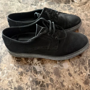 Svarta mockasneakers med snörning - Snygga svarta sneakers i mocka med klassisk snörning och rund tå. Skorna har en platt sula och stilren design som passar till det mesta. Perfekta för dig som gillar en enkel men trendig look.