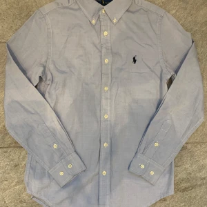 Blå skjorta från Ralph Lauren - Säljer denna riktigt feta Ralph lauren skjortan i suveränt skick! Den är i storlek 14 år vilket motsvarar xs ungefär!👍🏼