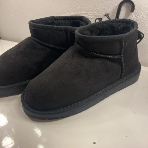 Svarta boots från 157, storlek 34/35 - Mysiga svarta boots från 157 i storlek 34/35. Skorna har en rund tå, platt sula och är fodrade med mjukt syntetmaterial för extra värme. Utsidan är i mockaliknande syntet och de har en enkel, stilren design som passar perfekt till kalla dagar.