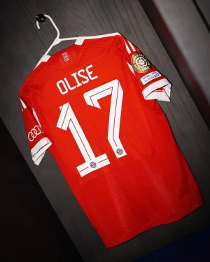 Röd Bayern München fotbollströja - Säljer en röd Bayern München fotbollströja med Olise och nummer 17 på ryggen. Tröjan har vita detaljer, korta ärmar och officiella klubbmärken samt FIFA World Cup patch på ärmen. Materialet är lätt och ventilerande polyester.