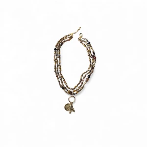 Handgjort vintage pärlhalsband med hänge - Unikt halsband med flera rader små pärlor i guld, brunt och svart. Halsbandet har ett stort guldfärgat hänge. Perfekt statement-piece för dig som gillar detaljer och coola accessoarer. Halsbandet är ihopsatt och omgjort av delar från vintage smycken, 90tal (skick därefter) helt unikt och one of a kind.  (Eftersom det är vintage så förekommer defekter och slitage så som exempelvis missfärgningar, se bilder)